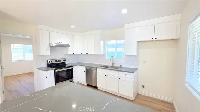 a kitchen with granite countertop a sink a stove a refrigerator and white cabinets