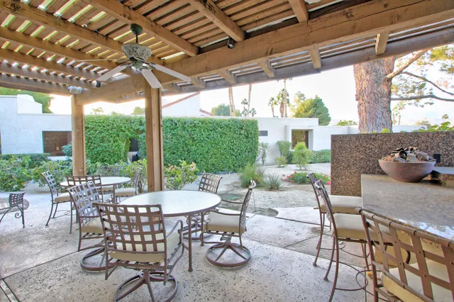 a view of a patio with table and chairs potted plants and floor to ceiling window
