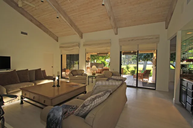 a living room with furniture a flat screen tv and a large window