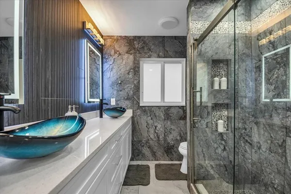 a bathroom with a granite countertop sink toilet and shower