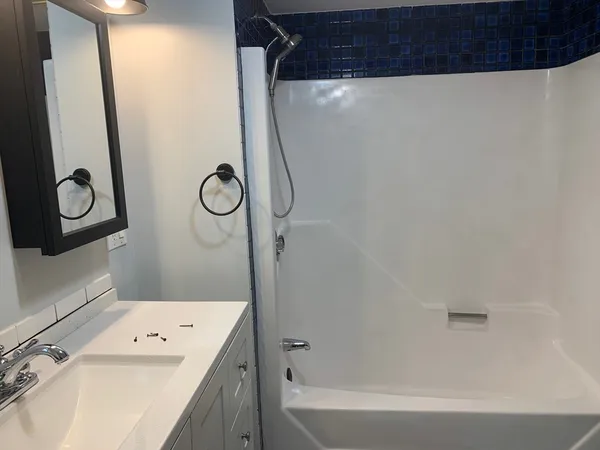 a bathroom with a granite countertop sink a mirror and a shower