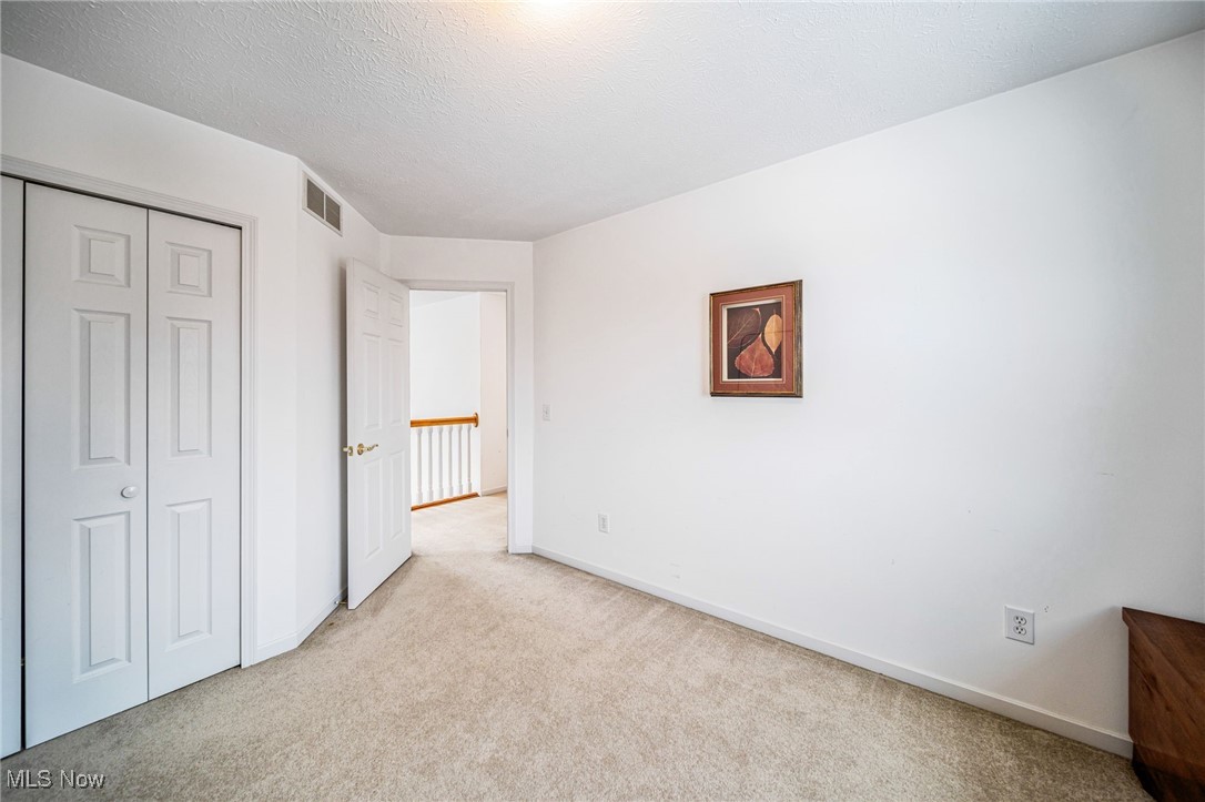 5955 South Ridge Road Madison, OH 44057 - Photo 28 of 42 Unfurnished bedroom featuring light colored carpet, a closet, and a textured ceiling