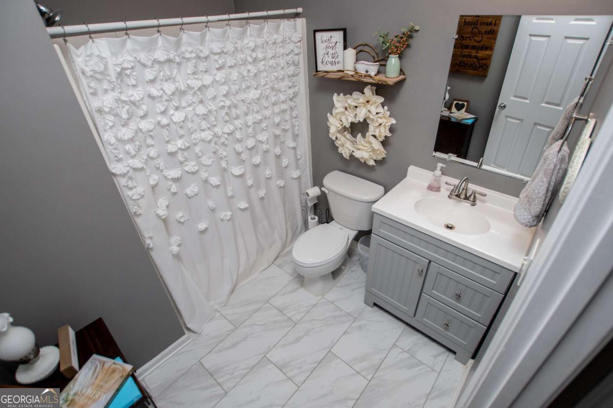 1074 Glenloch Road Roopville, GA 30170 - Photo 34 of 98 a bathroom with a sink a toilet and shower curtain