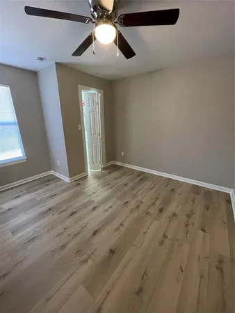 an empty room with wooden floor chandelier fan and windows