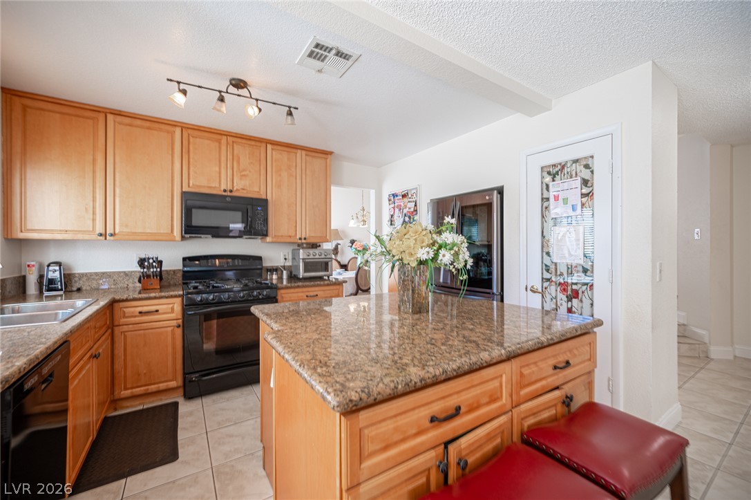 718 Rusty Spur Drive Henderson, NV 89014 - Photo 17 of 50 A well-appointed kitchen showcasing a central island and contemporary black appliances.