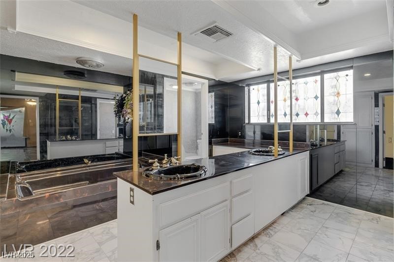 2249 Darwin Circle Henderson, NV 89014 - Photo 24 of 24 Kitchen featuring white cabinetry, light marble finish flooring, a textured ceiling, open floor plan, and dark stone countertops