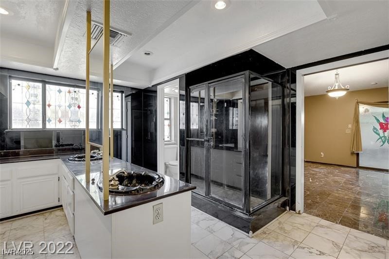 2249 Darwin Circle Henderson, NV 89014 - Photo 17 of 24 Kitchen with light marble finish flooring, a peninsula, white cabinets, a textured ceiling, and stainless steel gas stovetop