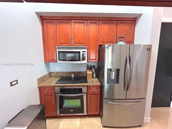 a kitchen with granite countertop a refrigerator and a stove top oven
