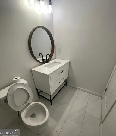 a bathroom with a toilet mirror vanity and a sink