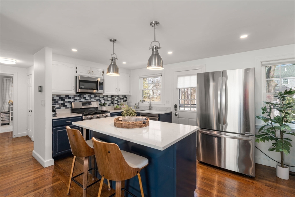 339 Weston Road Wellesley, MA 02481 - Photo 11 of 32 a kitchen with a refrigerator a stove a sink and a dining table with wooden floor