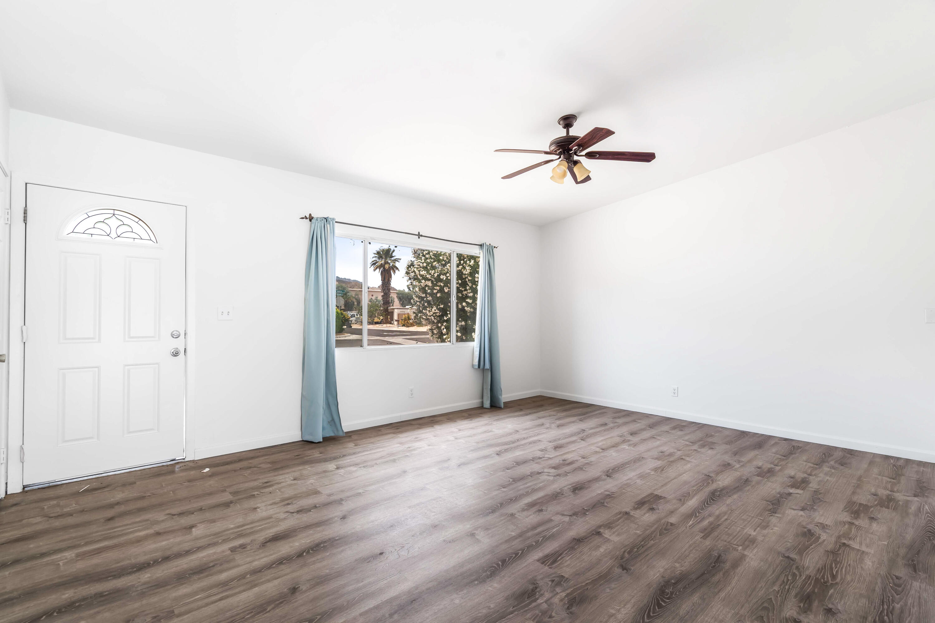43831 Joshua Road Palm Desert, CA 92260 - Photo 3 of 42 an empty room with wooden floor chandelier fan and windows