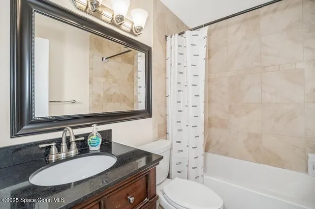 a bathroom with a granite countertop sink mirror toilet and bathtub