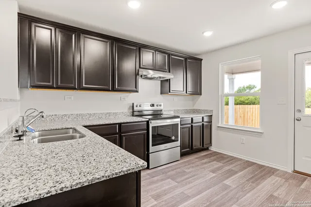 a kitchen with stainless steel appliances granite countertop wooden cabinets and a stove top oven
