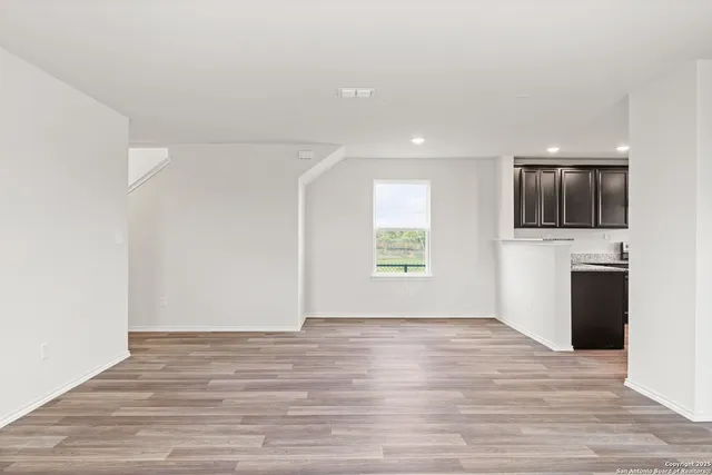 a view of an empty room with a window and a kitchen