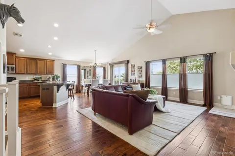 a living room with couches and kitchen view with wooden floor