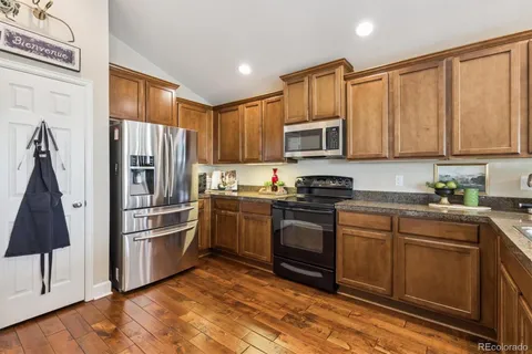 a kitchen with granite countertop a refrigerator stove and microwave
