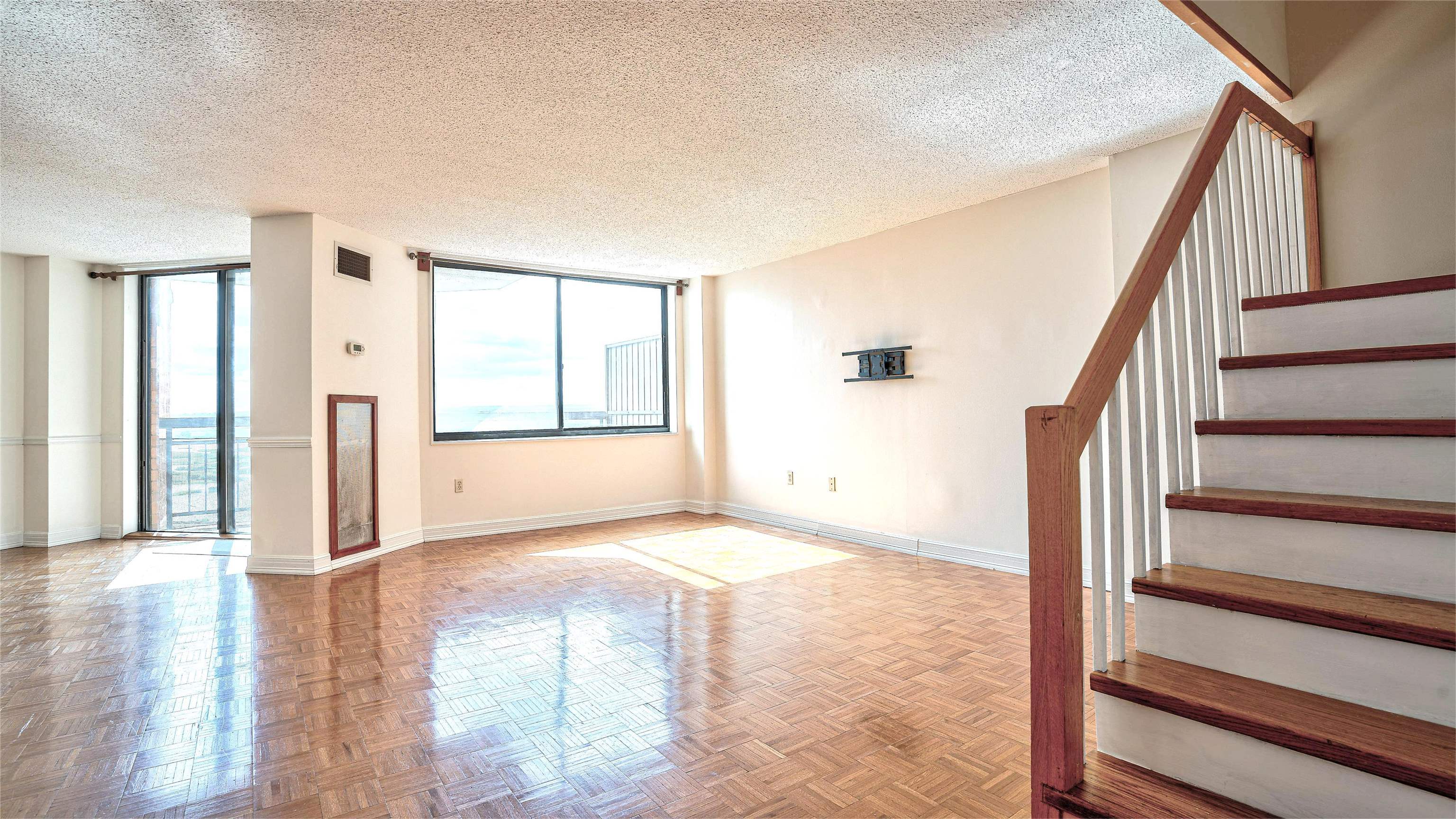 720 Harmon Cove Tower, Unit 720 Secaucus, NJ 07094 - Photo 4 of 49 a view of an empty room with wooden floor and windows