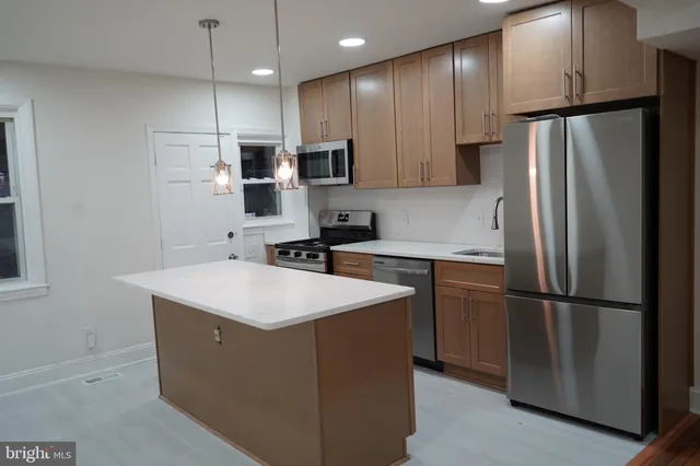 a kitchen with stainless steel appliances granite countertop a sink stove a refrigerator and white cabinets with wooden floor