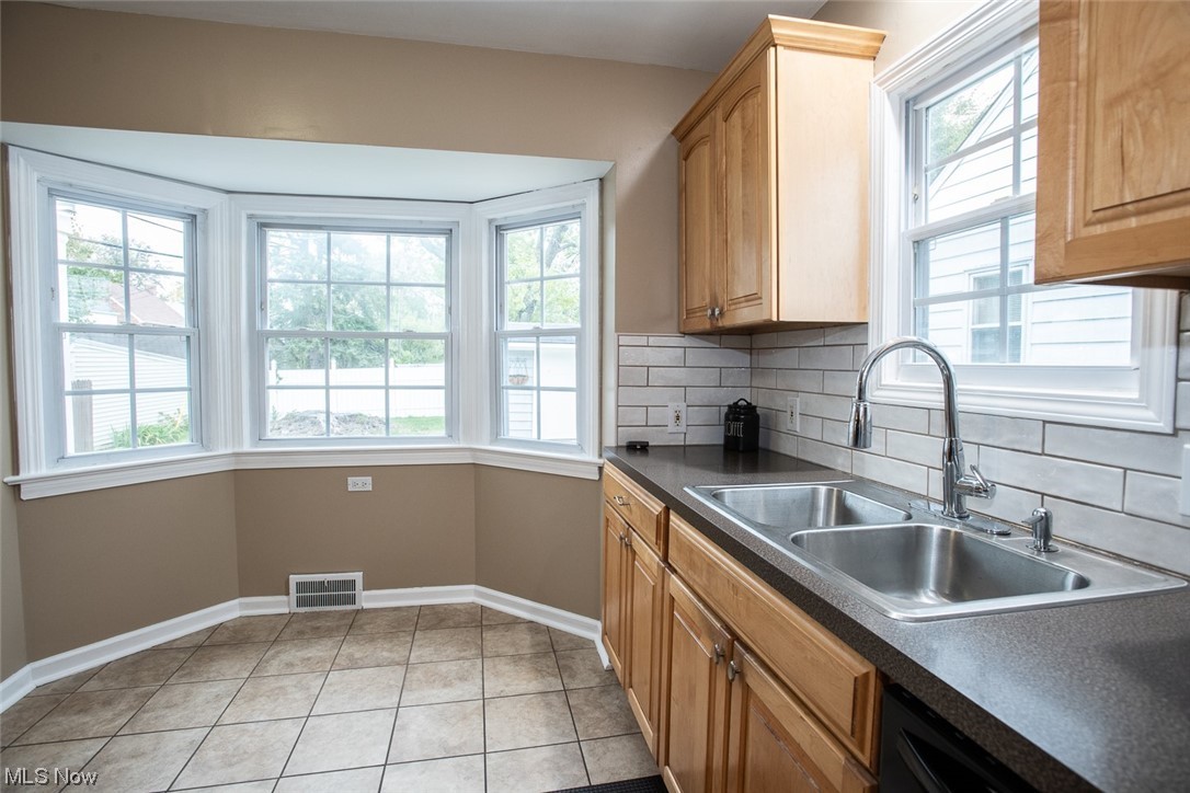 15716 Munn Road Cleveland, OH 44111 - Photo 8 of 24 Eat in kitchen with double steel sink, backsplash, light tile floors, and a wealth of natural light