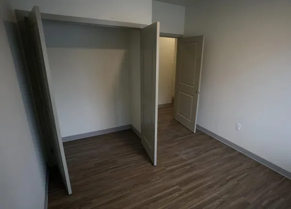 an empty room with wooden floor and closet