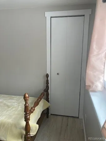 a bedroom with a bed wooden floor and a lamp