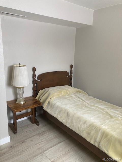 102 Third Street Berthoud, CO 80513 - Photo 26 of 35 a bedroom with a bed wooden floor and a lamp