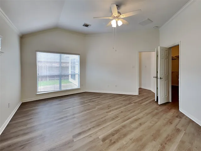 a view of empty room with wooden floor and fan