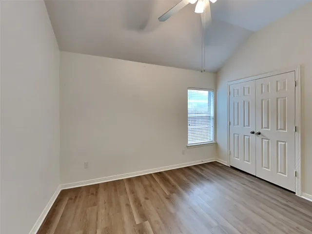 a view of an empty room with wooden floor and window
