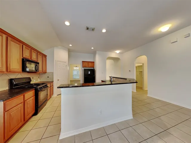 a large kitchen with stainless steel appliances a refrigerator a stove top oven and a sink