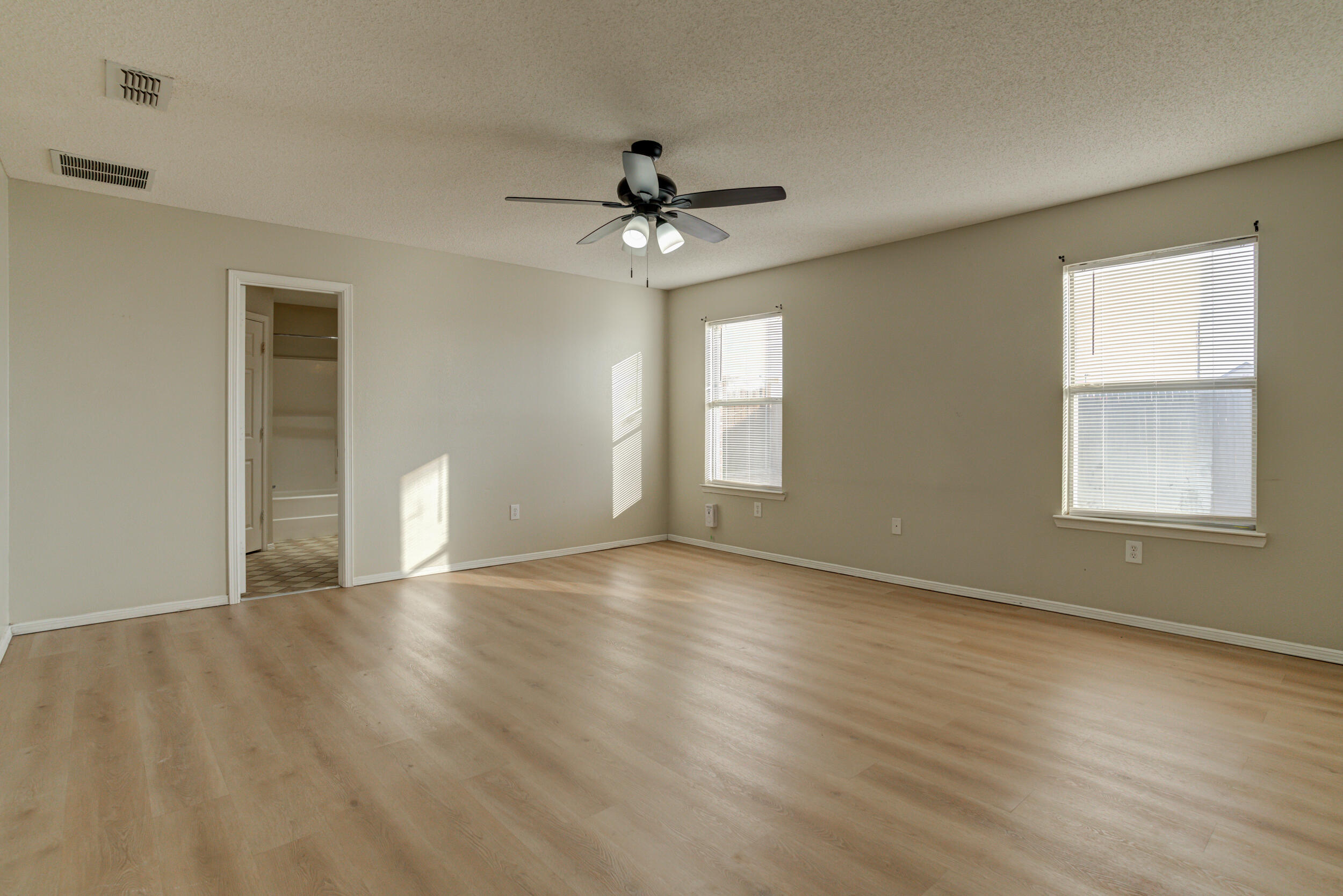 6221 18th Street Lubbock, TX 79416 - Photo 27 of 48 an empty room with wooden floor chandelier fan and windows
