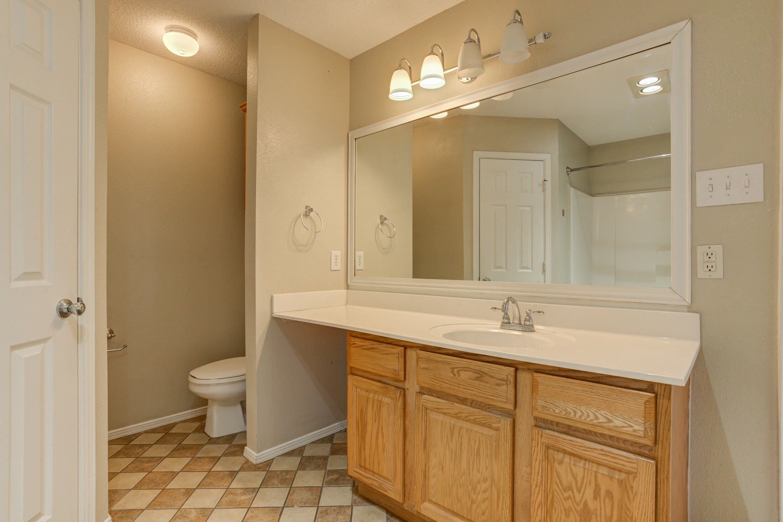 6221 18th Street Lubbock, TX 79416 - Photo 36 of 48 a bathroom with a sink a toilet a large mirror and shower