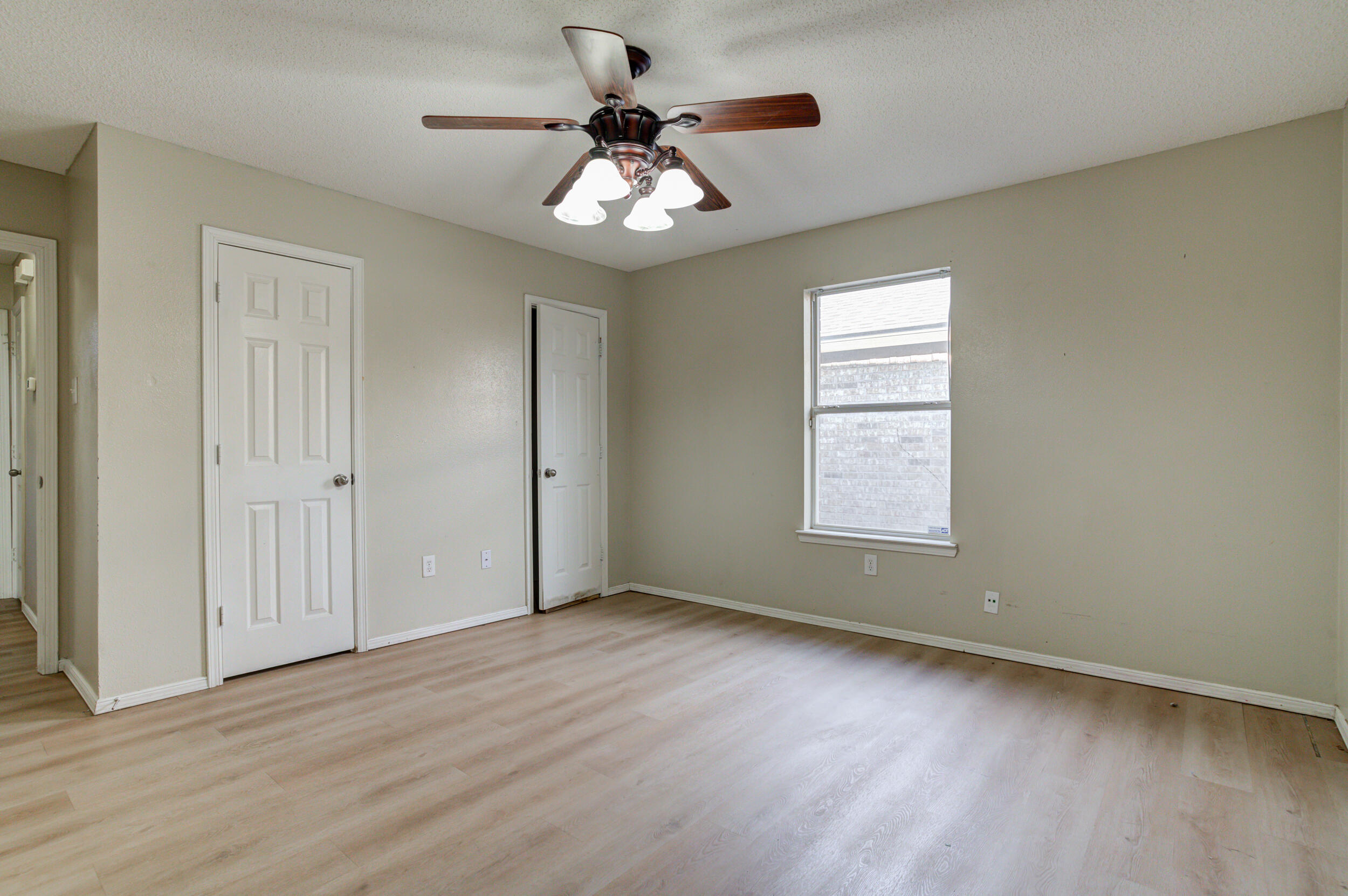 6221 18th Street Lubbock, TX 79416 - Photo 44 of 48 an empty room with wooden floor chandelier fan and windows