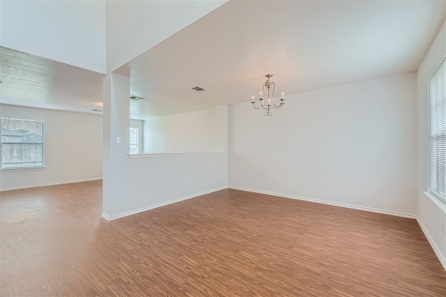 18408 Cloudmore Lane Elgin, TX 78621 - Photo 3 of 11 A classic chandelier illuminates the room, featuring sleek hardwood flooring and ample window light.