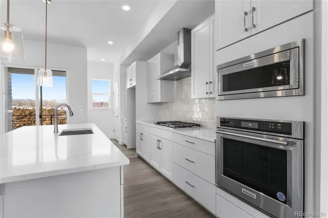 a view of a kitchen island a sink wooden floor and chandelier