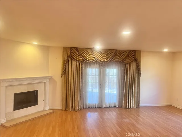 an empty room with wooden floor fireplace and windows