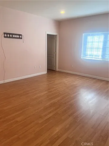 a view of an empty room with wooden floor and closet