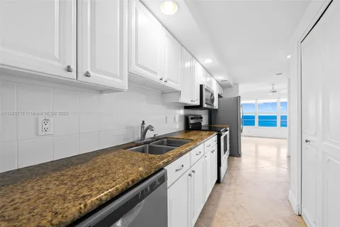 a kitchen with granite countertop white cabinets and stainless steel appliances