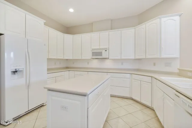 a large white kitchen with granite countertop a sink and white cabinets