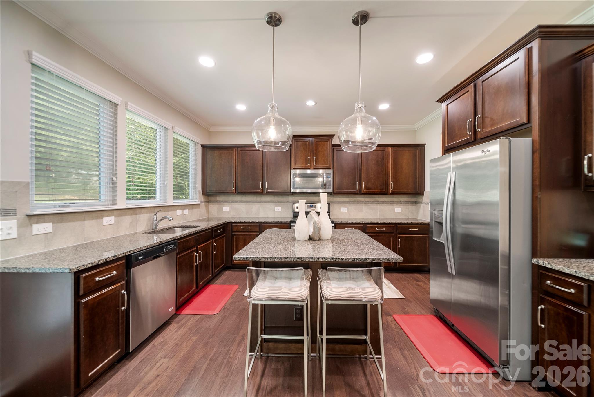 8122 Mossy Rock Road Waxhaw, NC 28173 - Photo 8 of 28 a kitchen with stainless steel appliances granite countertop a sink a stove a refrigerator white cabinets and wooden floor
