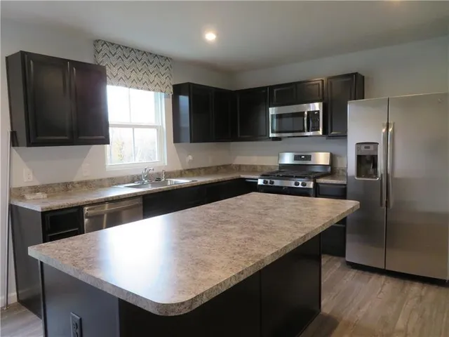 a kitchen with stainless steel appliances granite countertop a sink dishwasher a refrigerator a microwave oven with granite countertops and cabinets