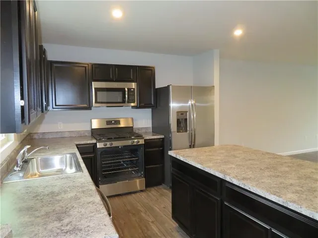 a kitchen with granite countertop a refrigerator and a stove top oven