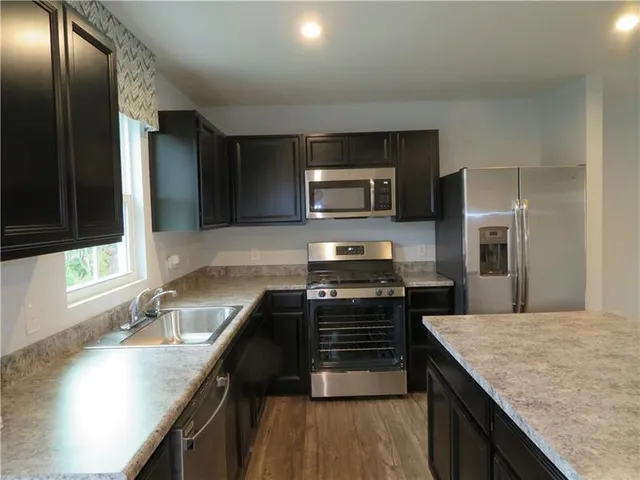 a kitchen with stainless steel appliances granite countertop a sink a stove and microwave
