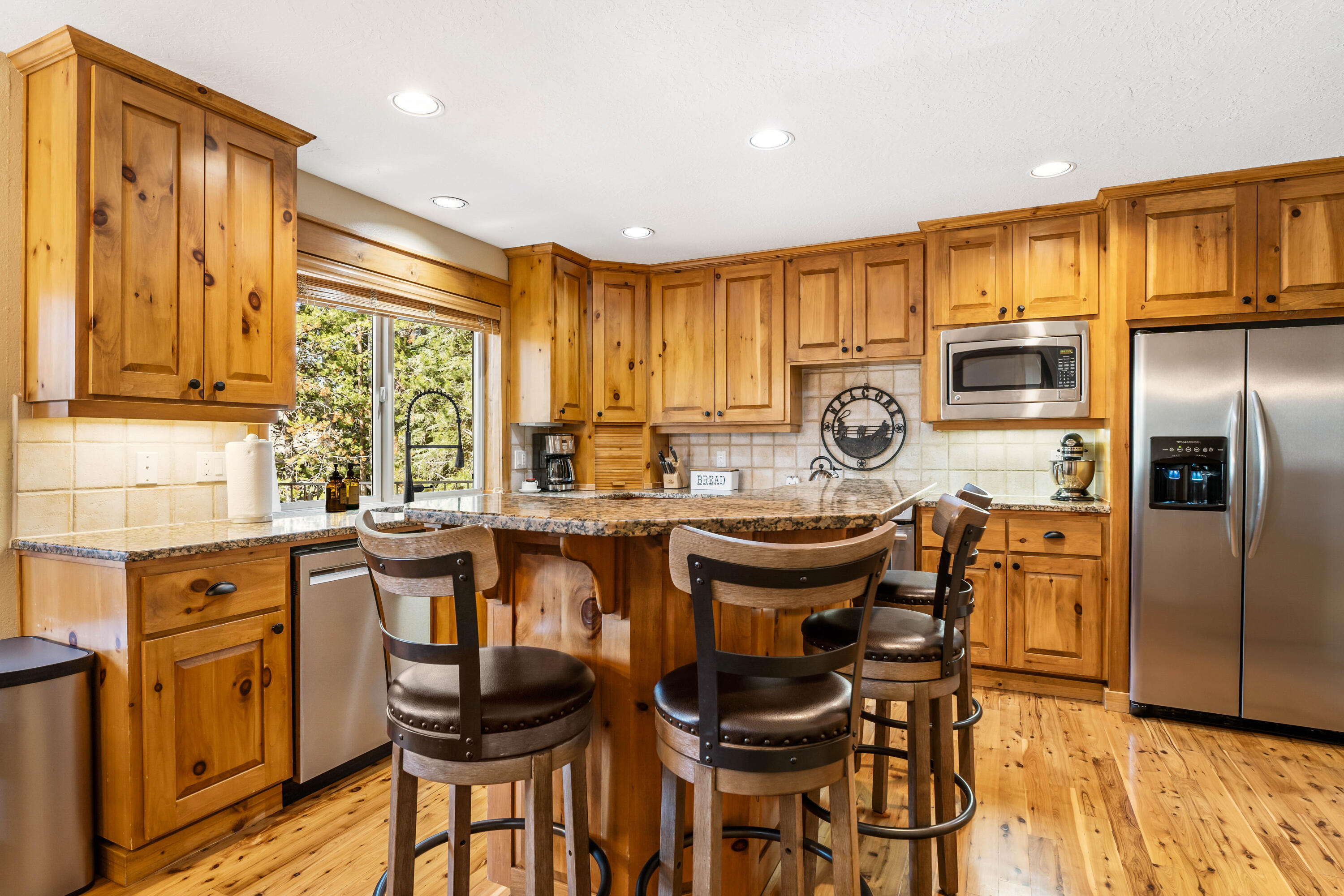 18189 Oregon Loop, Unit 5 Sunriver, OR 97707 - Photo 3 of 41 This inviting kitchen showcases natural wood cabinetry, granite countertops, and stainless steel appliances, all beautifully framed by a large window.