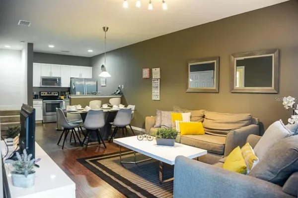 a living room with furniture kitchen view and a wooden floor