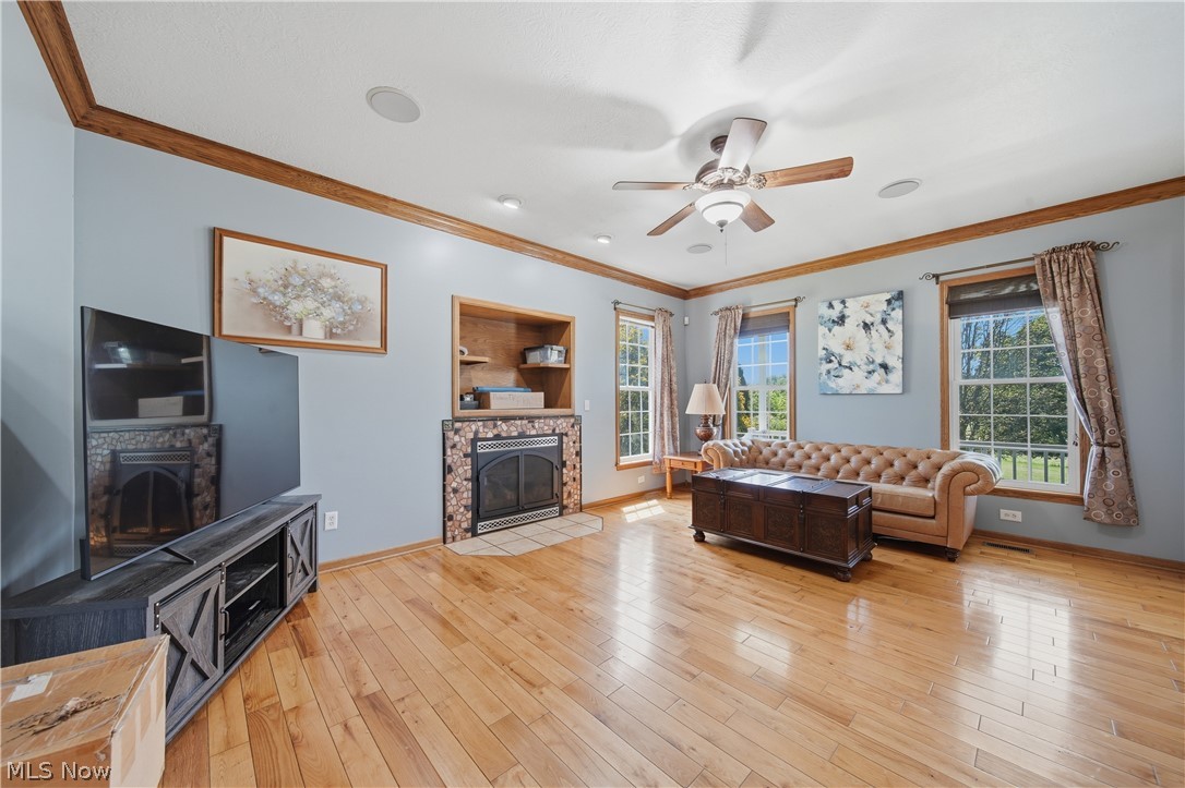 12159 Lawndell Road Southwest Beach City, OH 44608 - Photo 16 of 49 Living area featuring wood-finish flooring, a built-in fireplace with a tiled surround, recessed shelving, and a ceiling fan