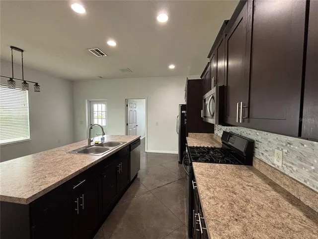 a large kitchen with granite countertop stove top oven and cabinets