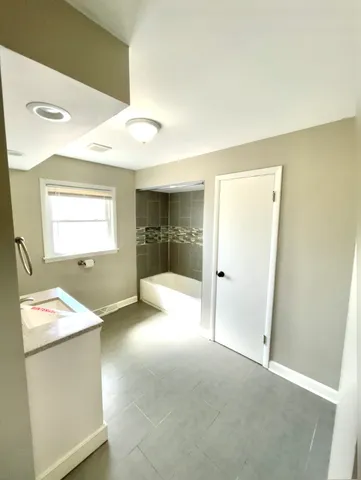 a view of an empty room with window and a kitchen