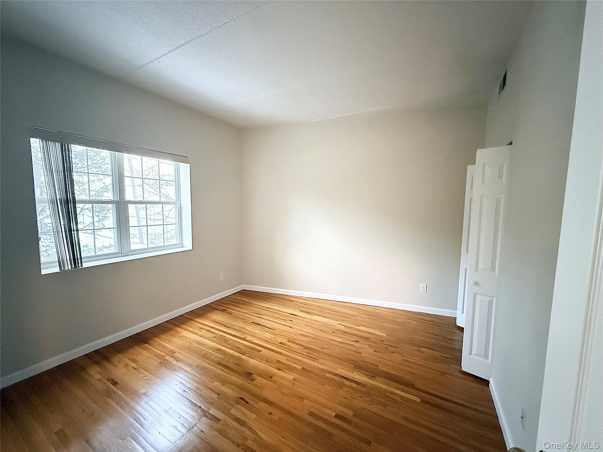 70 Lime Kiln Road, Unit 1A Tuckahoe, NY 10707 - Photo 3 of 10 an empty room with wooden floor and windows
