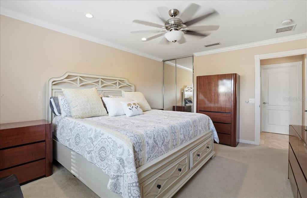 5546 Modena Place Sarasota, FL 34238 - Photo 21 of 67 a spacious bedroom with a bed and a chandelier