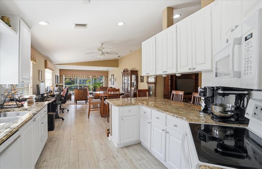 5546 Modena Place Sarasota, FL 34238 - Photo 5 of 67 a kitchen with a sink dishwasher stove and white cabinets with wooden floor